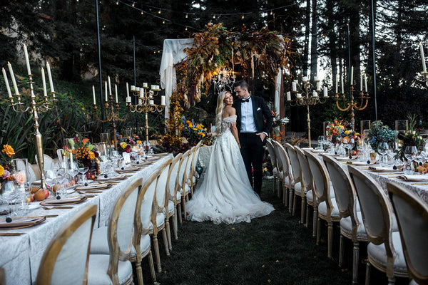 Bride and groom stand in front of sweetheart table at wedding reception full of 2023 wedding color trends